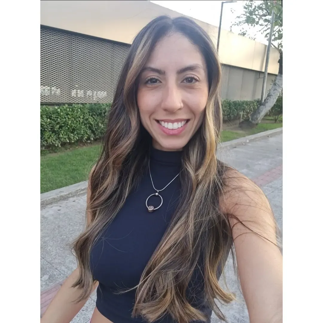 Carol sorrindo numa selfie ao ar livre, de cabelo solto