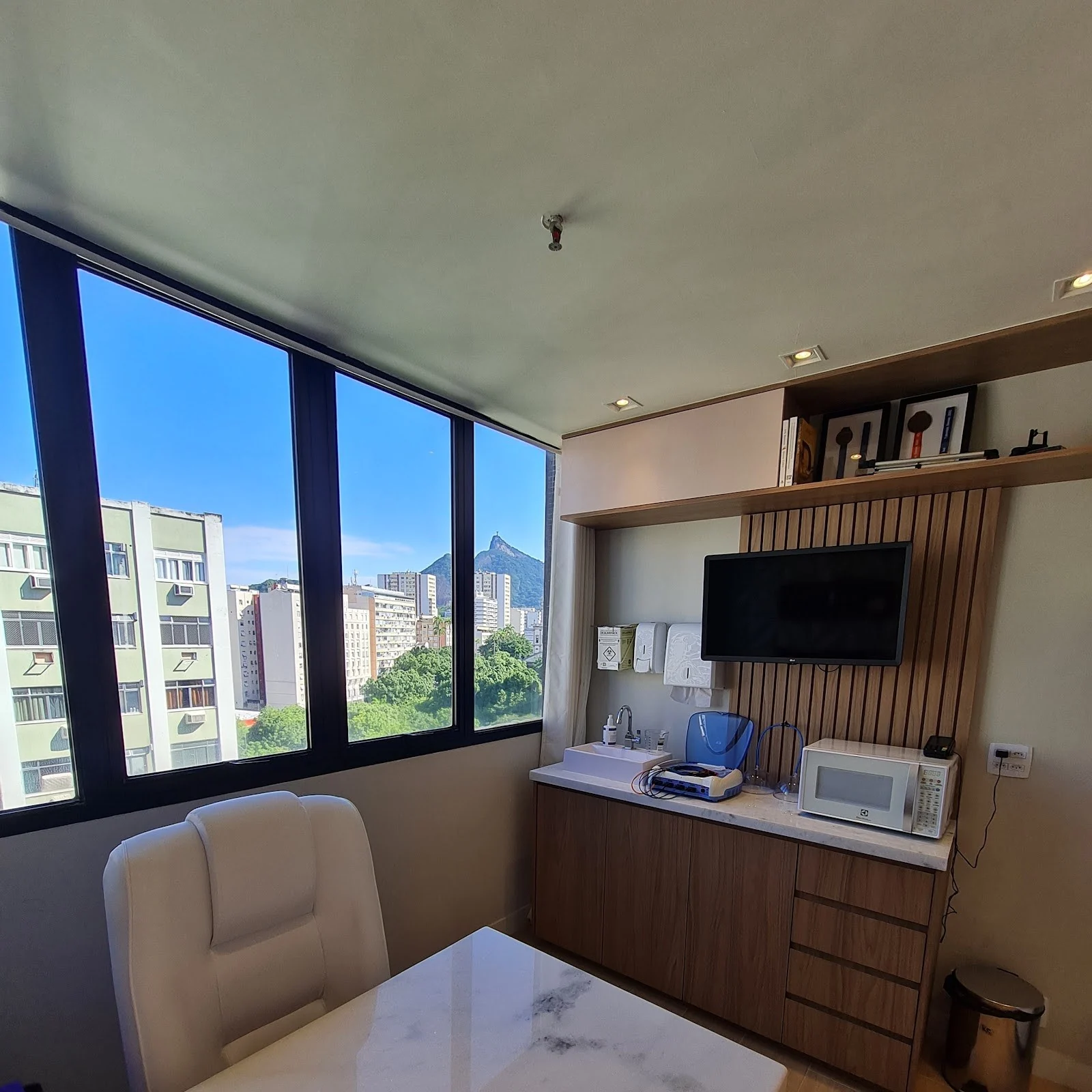 Sala de atendimento com mesa de mármore, poltrona e janela com vista para o morro do Corcovado